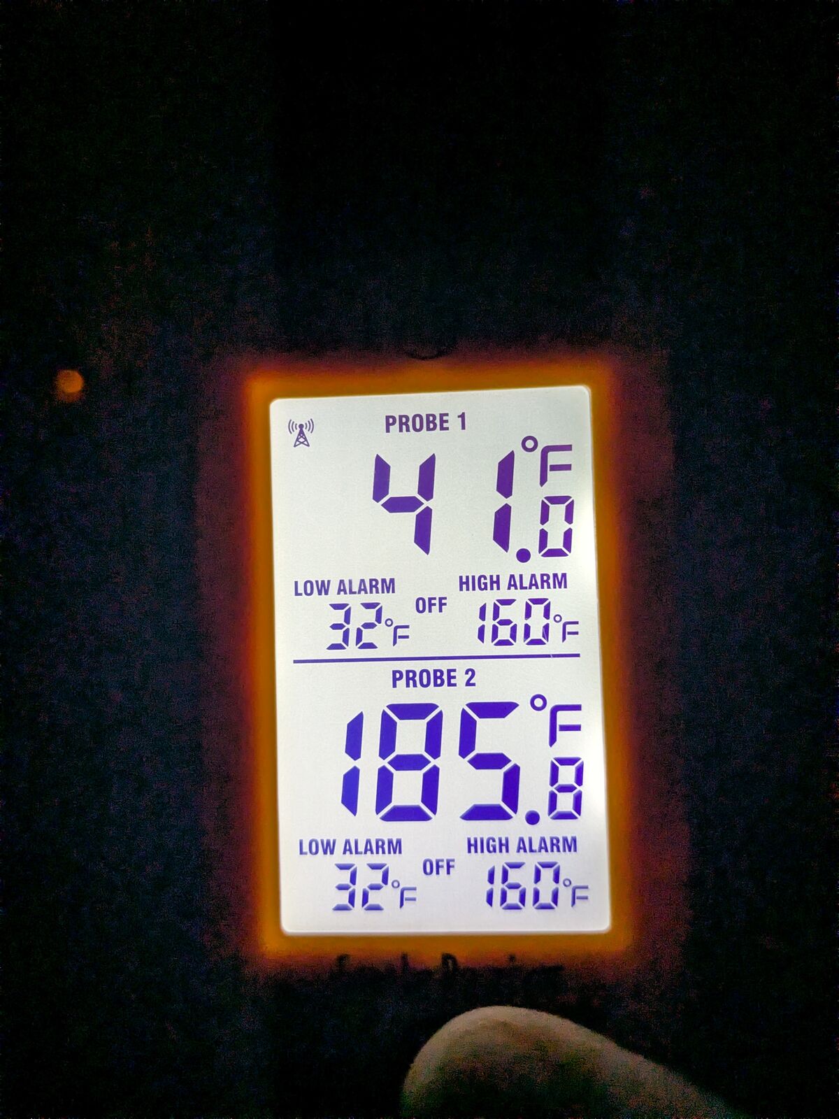 ThermoWorks Smoke receiver glowing in the dark, showing meat probe at 41.0°F and pit probe at 185.8°F.